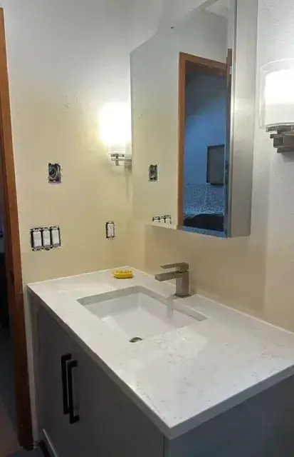 Finished drywall around a new vanity and mirror in a remodeled bathroom