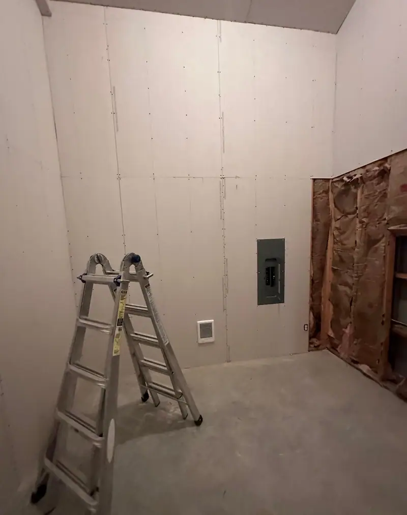 Shop room hung in drywall from the slab to the ceiling, with a ladder in the corner