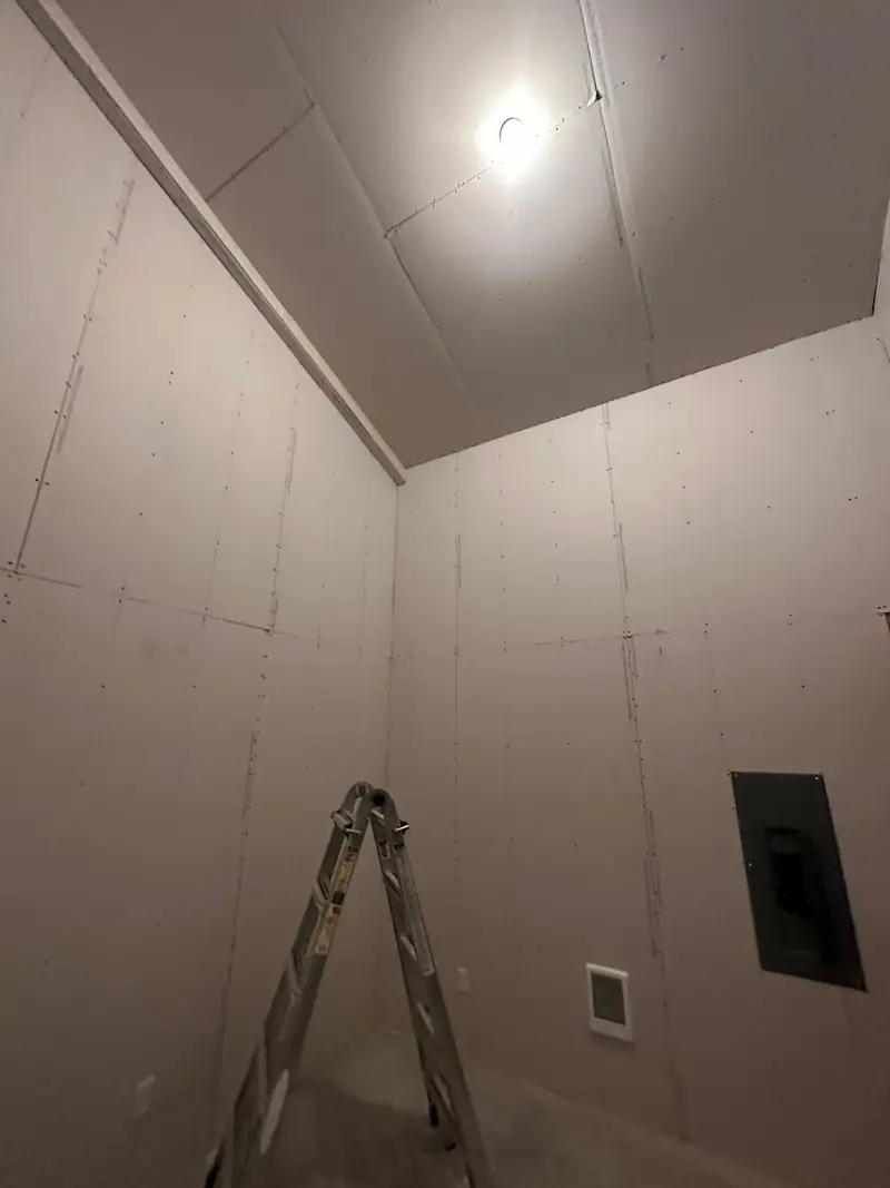 Tall room with the walls and sloped ceiling hung in drywall
