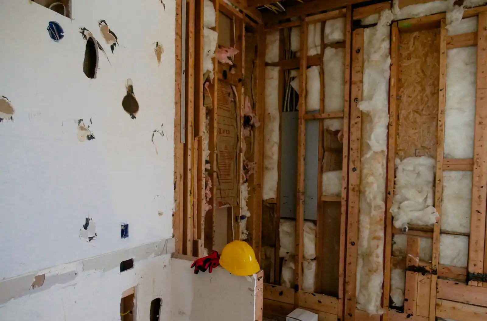 Gutted room with holes cut through the old drywall and open stud bays
