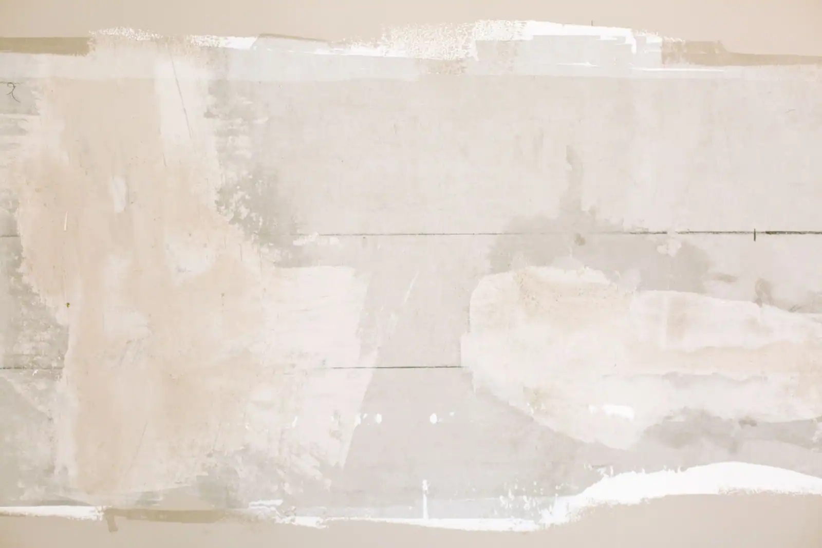 Band of dried joint compound feathered out across a tan wall