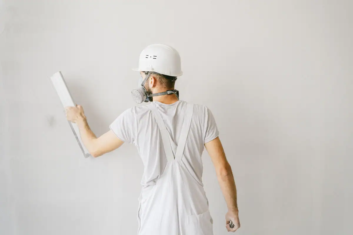 Finisher drawing a wide skimming blade down a wall