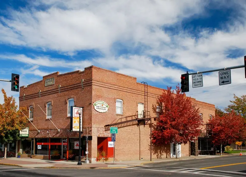 Red-brick Odd Fellows building on a downtown corner in Madras, Oregon, with autumn trees