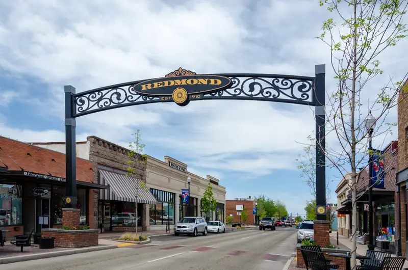 The wrought-iron Redmond arch over a downtown street of brick storefronts in Redmond, Oregon